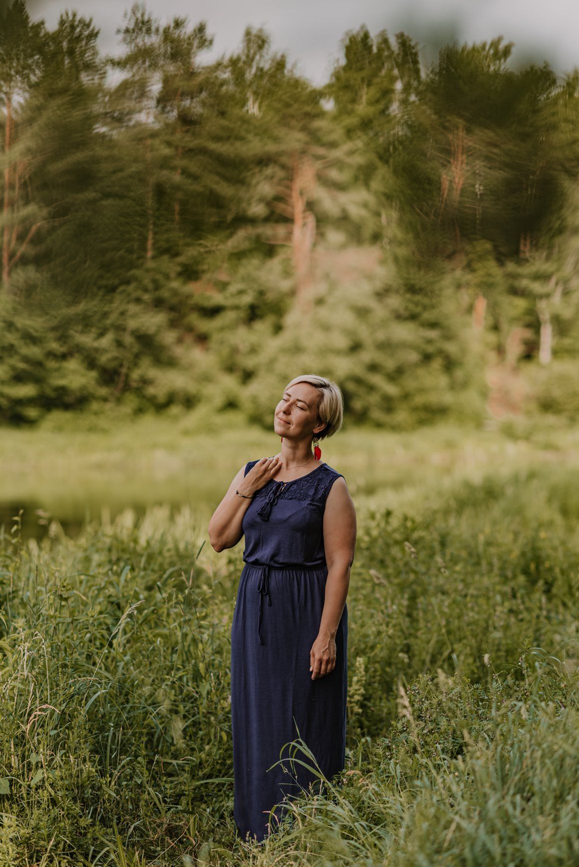 A flowing navy blue dress catches the summer breeze in a natural meadow setting.