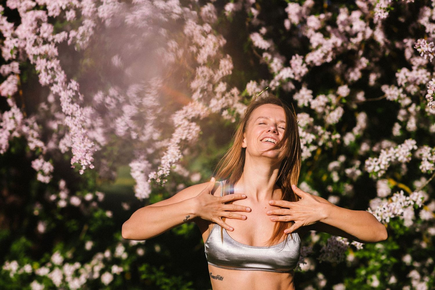 Portrait session beneath blooming cherry blossom trees with pink flowers.