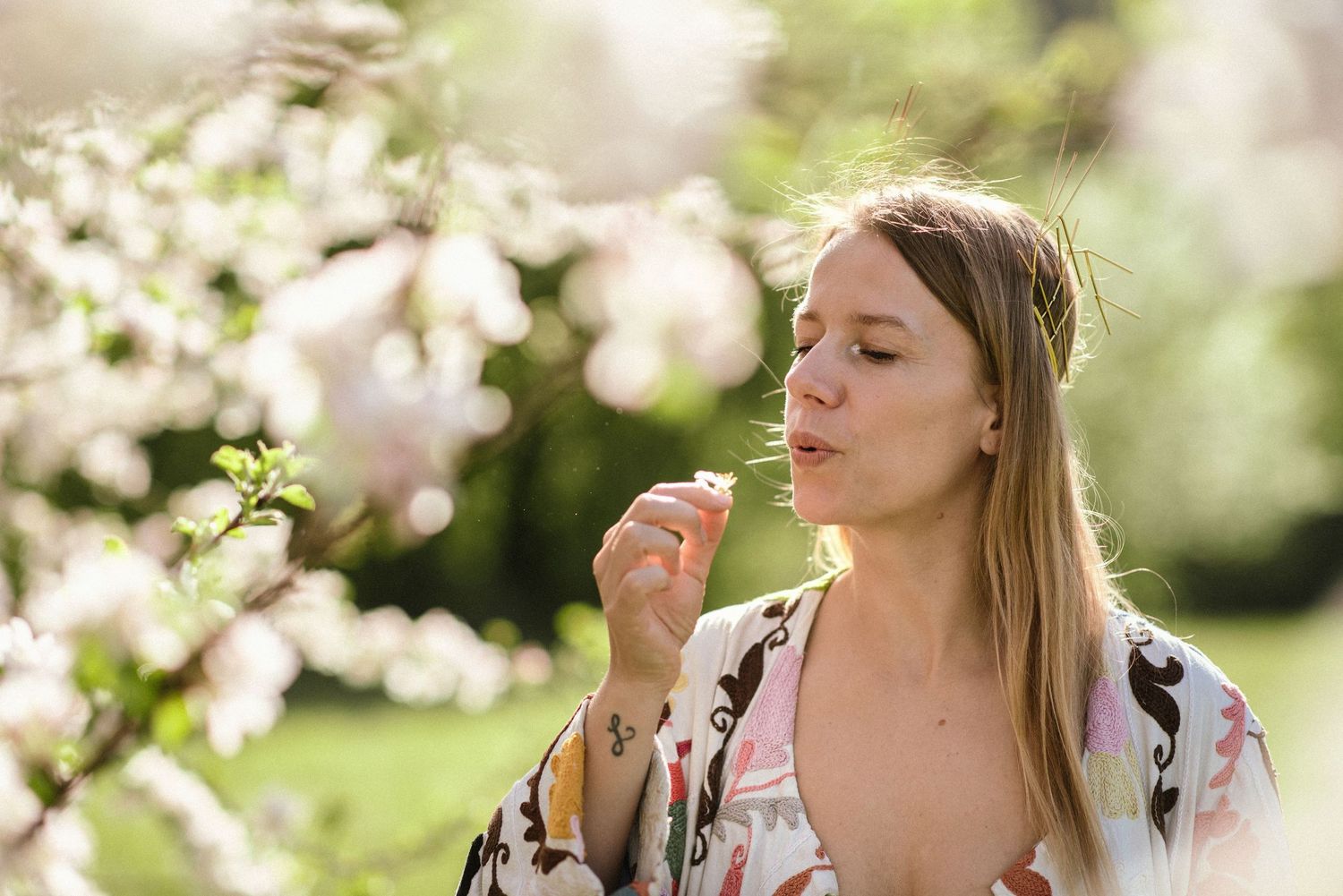 Elegant outdoor portrait with blooming spring flowers and natural sunlight.