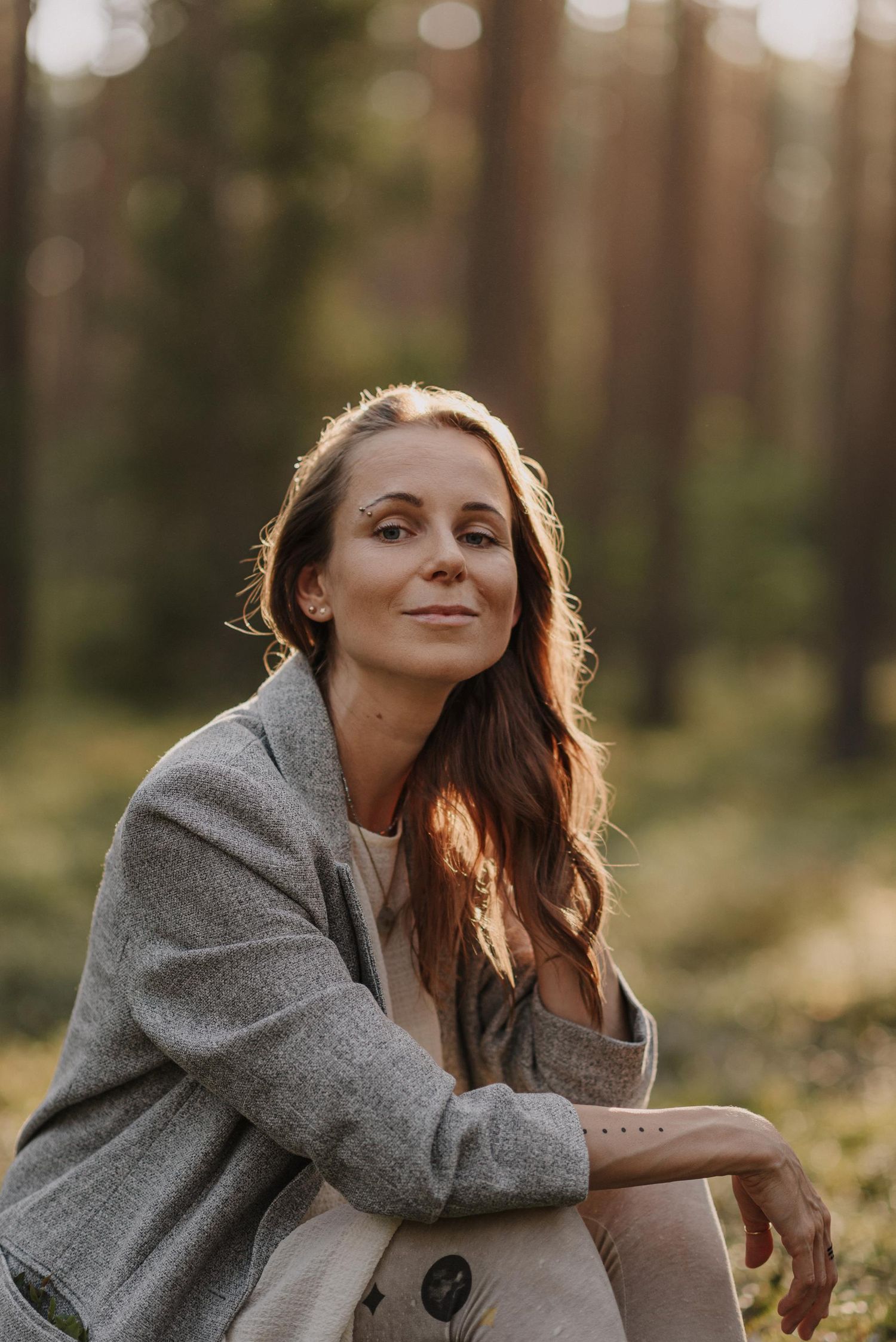 Outdoor portrait in warm sunlight featuring casual gray blazer and natural styling.