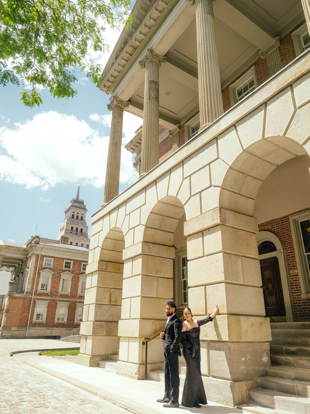 Romantic photo shoot on stone steps of neoclassical building with grand white columns and arches.