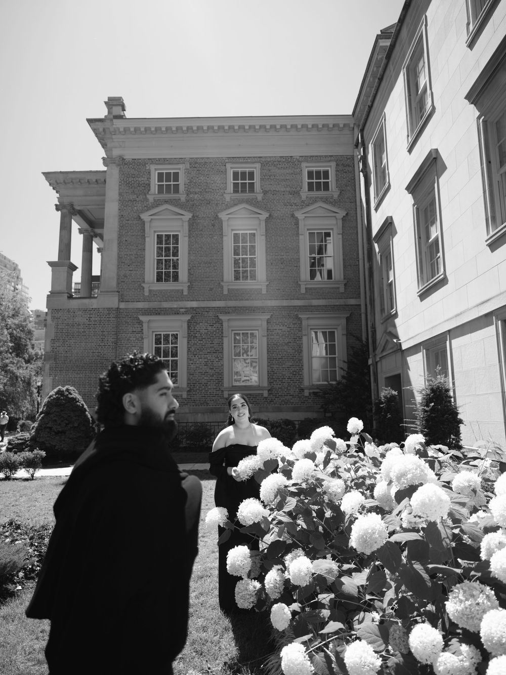 A romantic black and white photo sequence with white hydrangea bushes in front of a historic building.