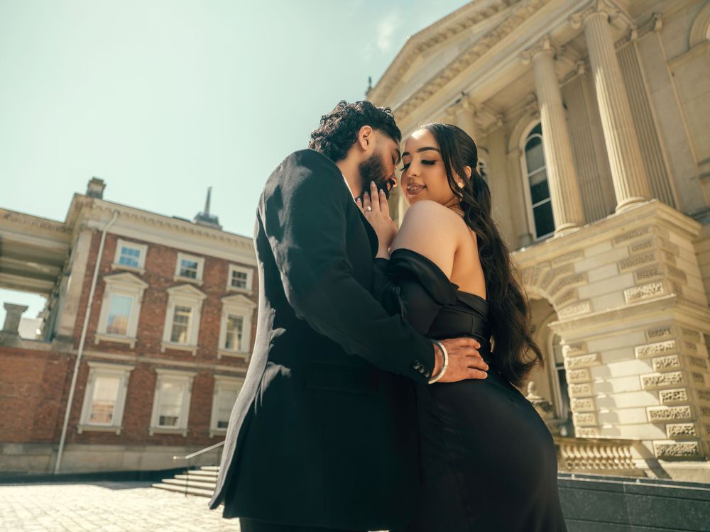 Intimate moment captured between couple during golden hour at historic building entrance with classical architecture.