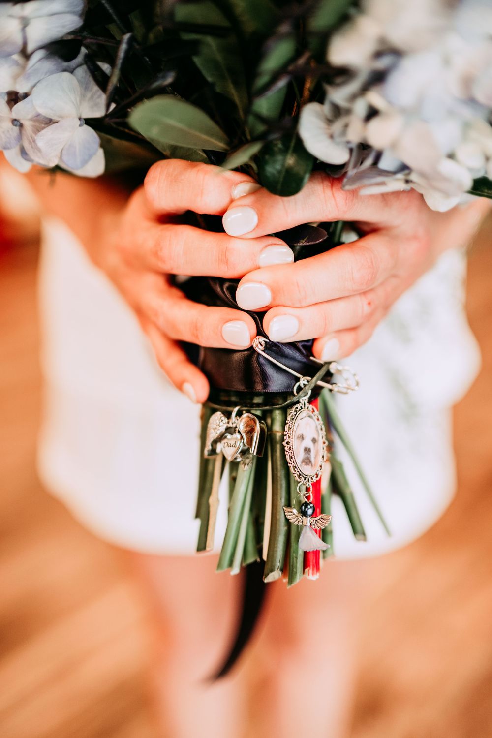 A series of close-up shots showing hands holding a bridal bouquet wrapped with decorative jeweled charms and ribbons.
