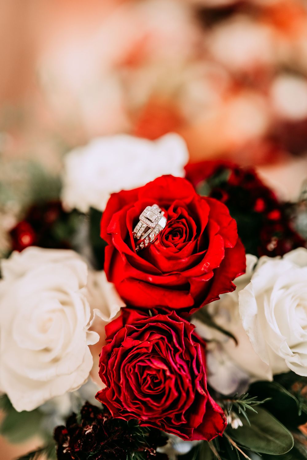 Red and white roses arranged in an elegant floral display with green foliage in a romantic color scheme.