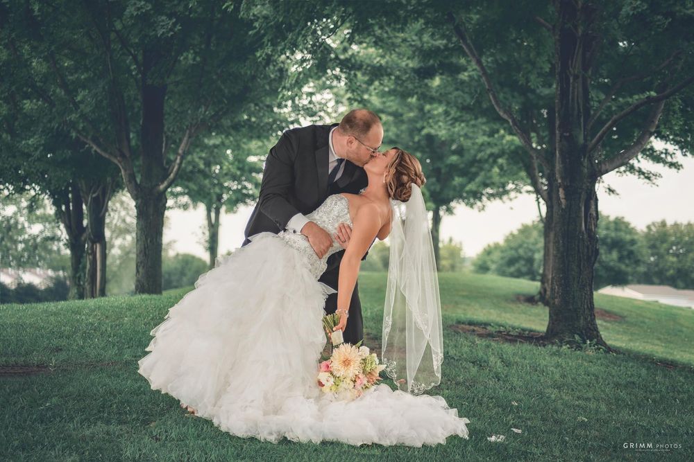 Elegant wedding couple embracing under tree canopy in natural lighting.