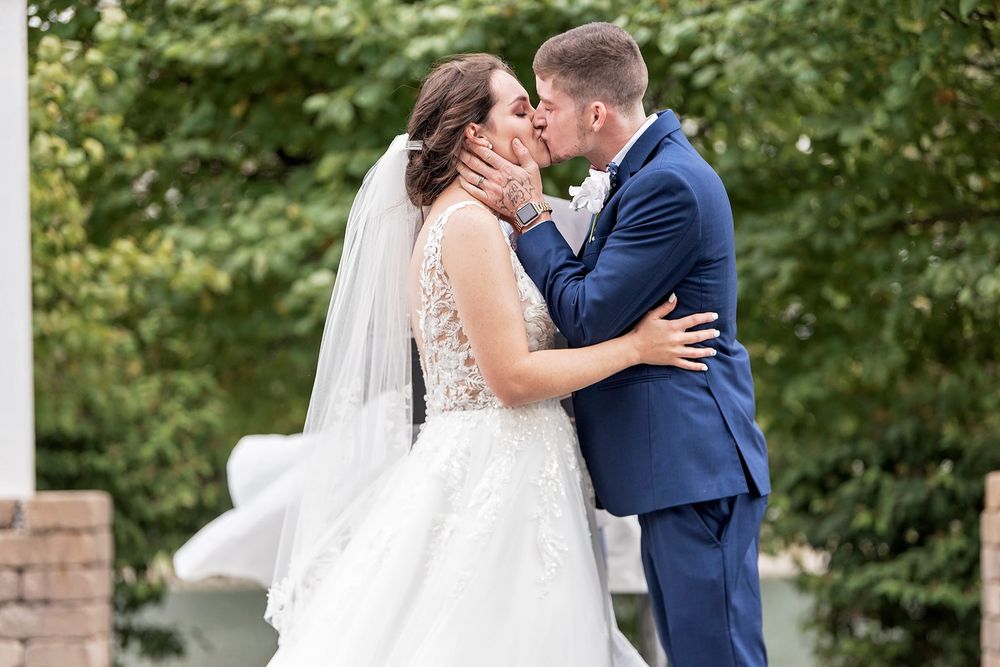 Romantic wedding couple moments captured outdoors with natural greenery backdrop.
