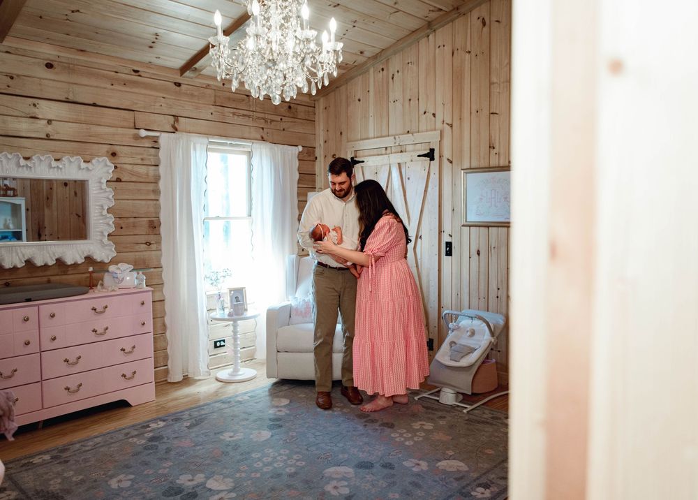 Interior shots of rustic nursery with wooden walls and pink furniture.