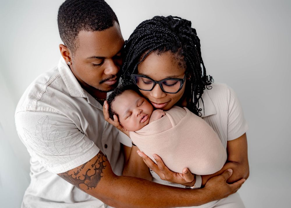 Family embracing in tender moments against grey backdrop wearing white shirts.