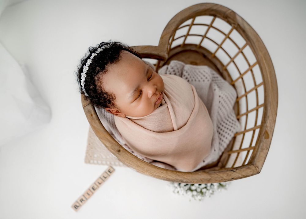 Woven basket cradle holds sleeping infant in minimalist setting.