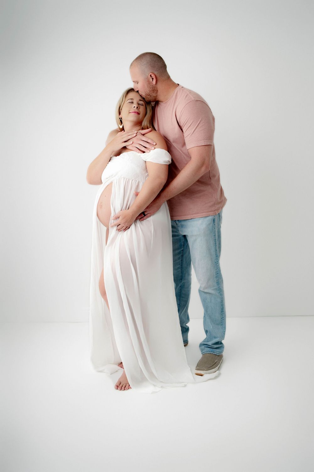 Couple in casual wear sharing intimate moments against white backdrop.