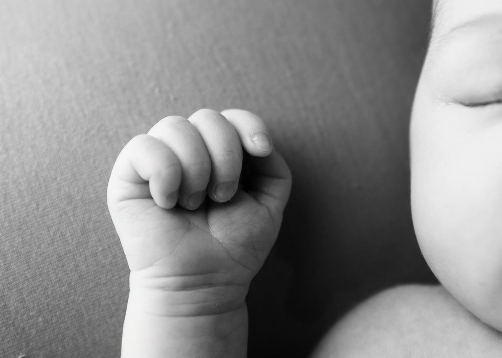 Close-up black and white detail shots of a baby's tiny hands and feet.