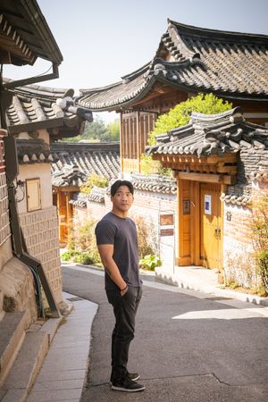Tourist posing along stone pathways in traditional Korean hanok village.