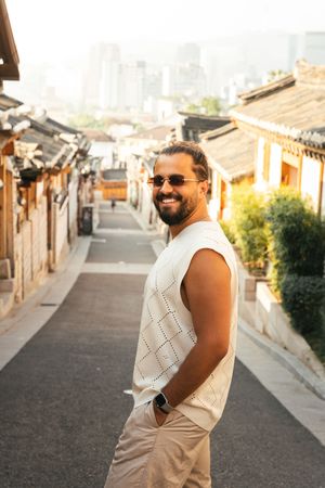 Tourist explores scenic hillside alley in Korean traditional village during golden hour.