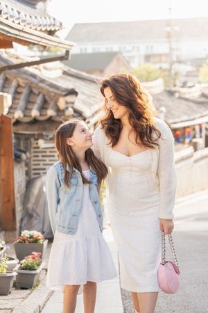 Two people in light summer outfits walking through historic Korean neighborhood streets.