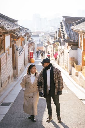 Couple strolling through historic stone-walled alleyways of a traditional Korean neighborhood.