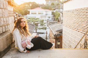 Tourist relaxes on stone steps during sunset in traditional Korean village.