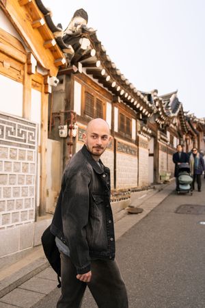 Tourist exploring the geometric patterns of traditional Korean hanok village walls and architecture.