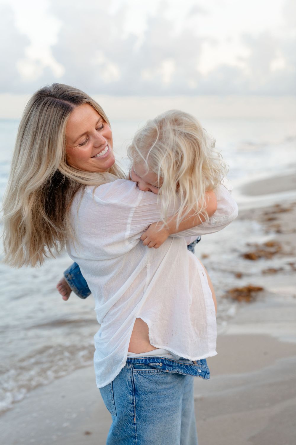 A joyful moment shared between a parent and child playing together on a beach at sunset.
