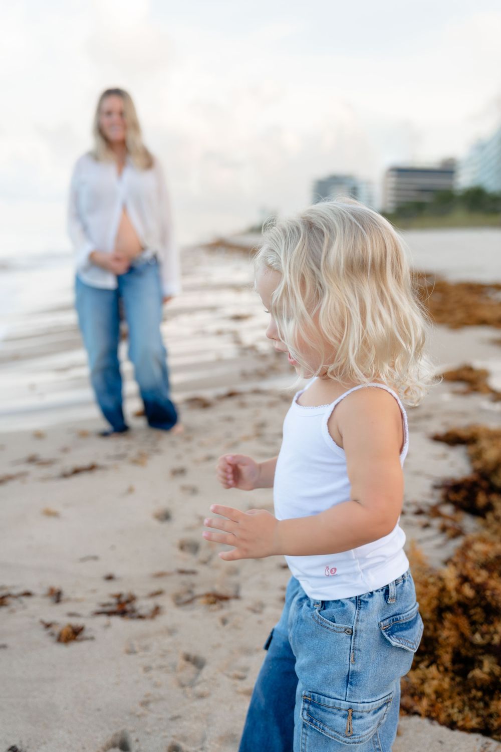 Two people in matching denim outfits enjoy a playful moment at the beach.