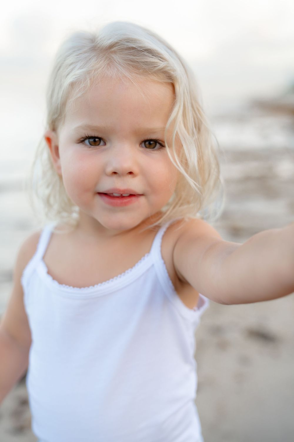 A series of close-up portraits showing a happy toddler with light blonde hair wearing a white sleeveless top.