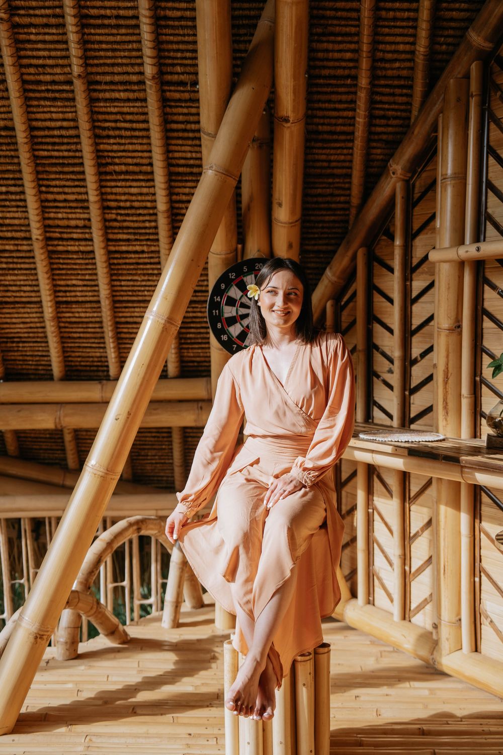 Interior view of bamboo architecture with person in flowing dress seated.
