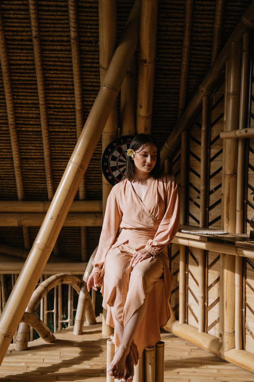 Peaceful scene in bamboo structure with person in peach dress relaxing.