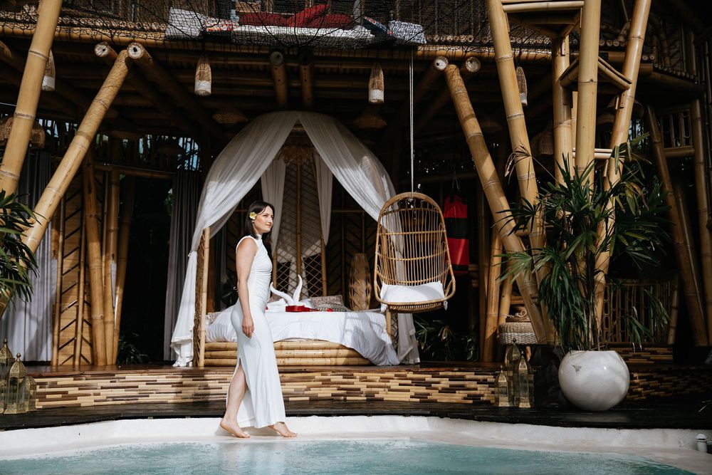 Elegant bamboo lounge area with white curtains and tropical decor.