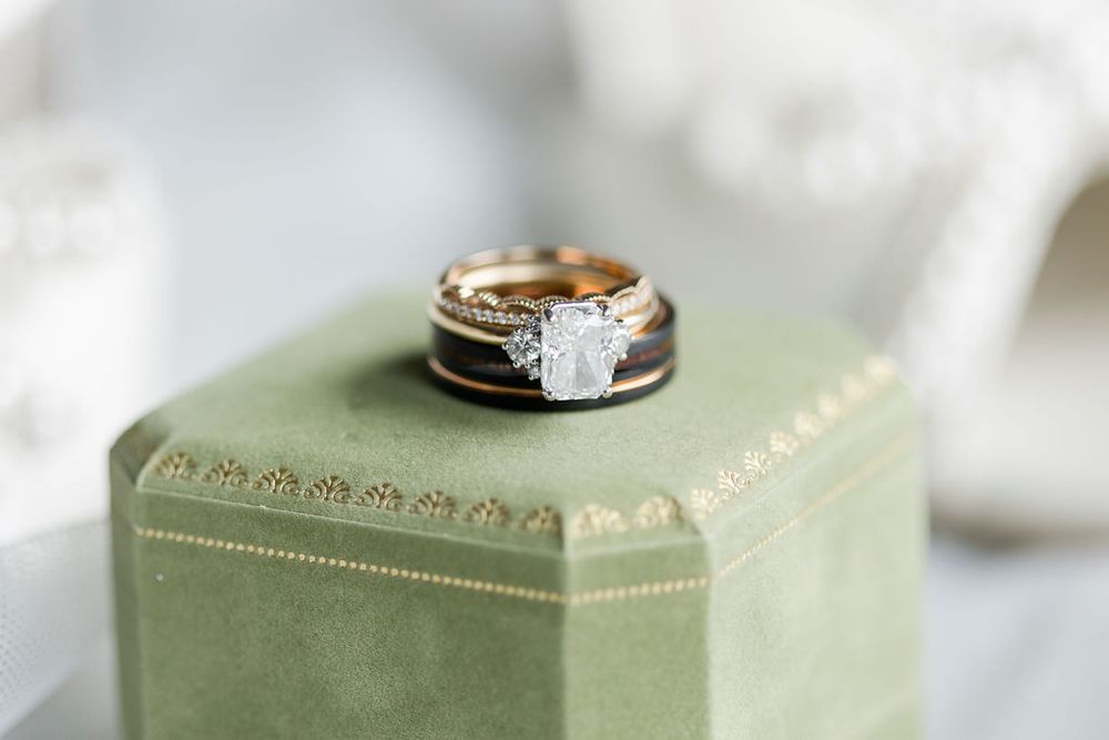 Wedding rings displayed on a sage green hexagonal box with decorative details.