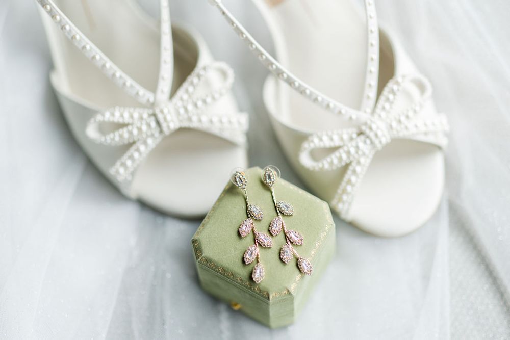 White baby shoes with delicate lace details arranged on a light background.