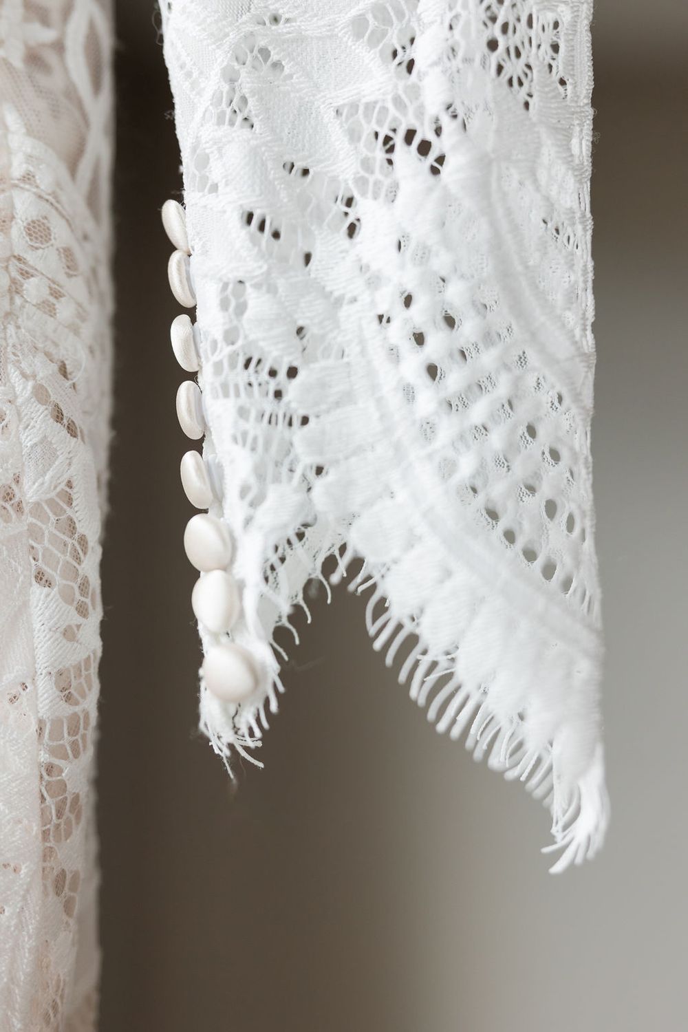 Close-up detail of delicate white lace fabric with scalloped edges and intricate patterns.