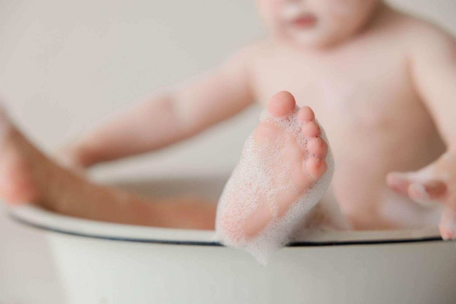 Close-up of tiny baby foot against white surface showing delicate details and soft skin.