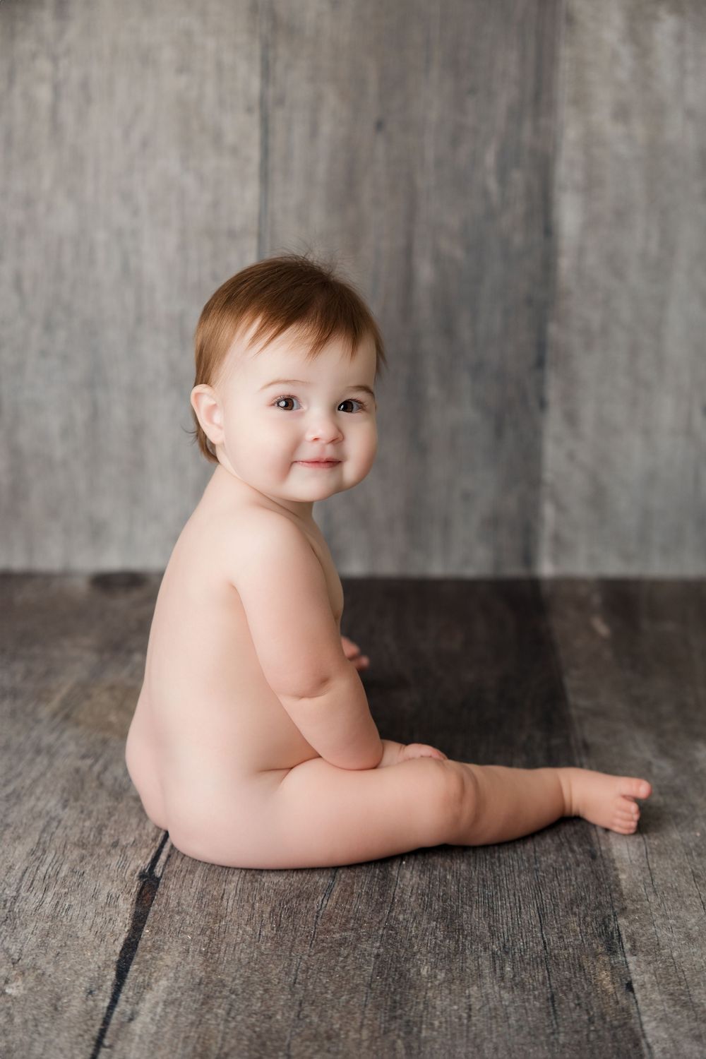 Series of five black and white artistic photos showing a baby lying on rustic wooden flooring.