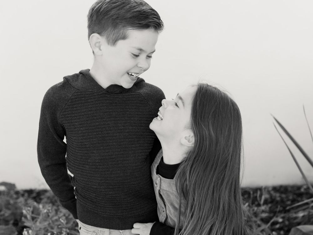 black and white portrait of brother and sister laughing together
