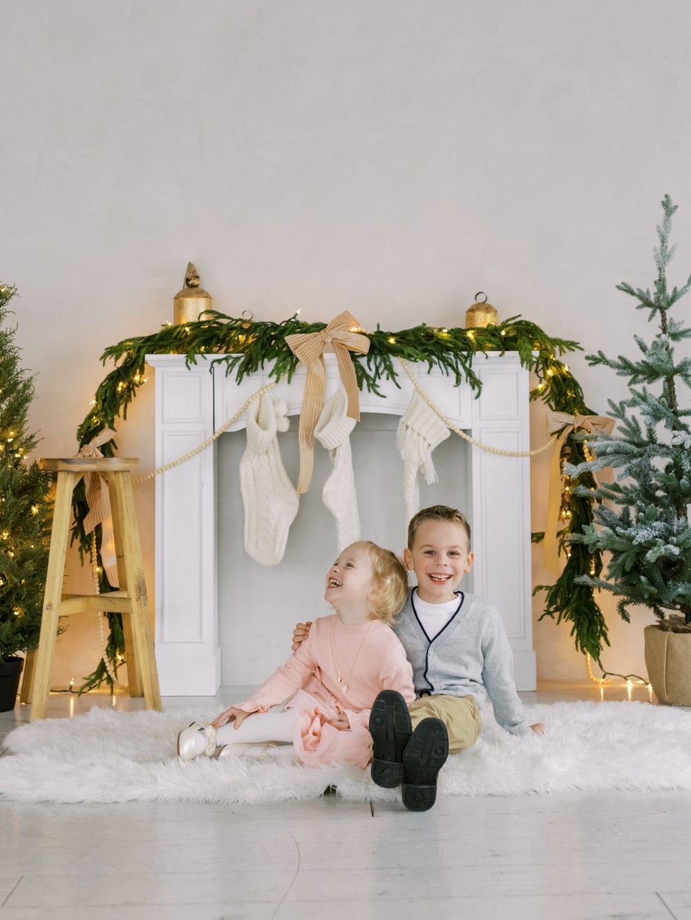 Siblings at mantle with white and gold Christmas decorations fresh garland at White Space Studios