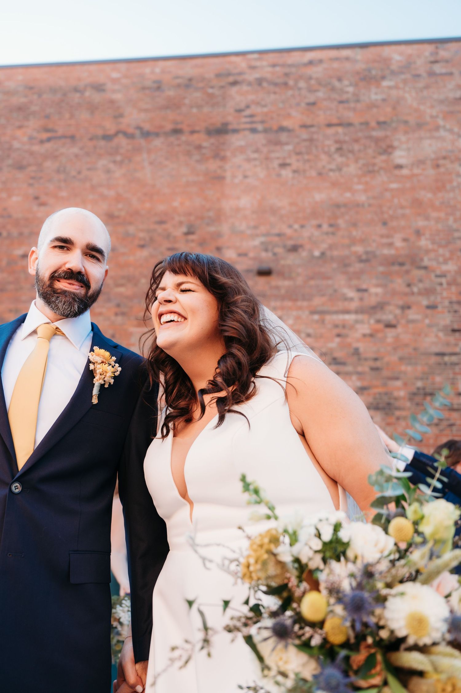 Candid of bride and groom with brick building backdrop in downtown des moines iowa by des moines wedding photographer