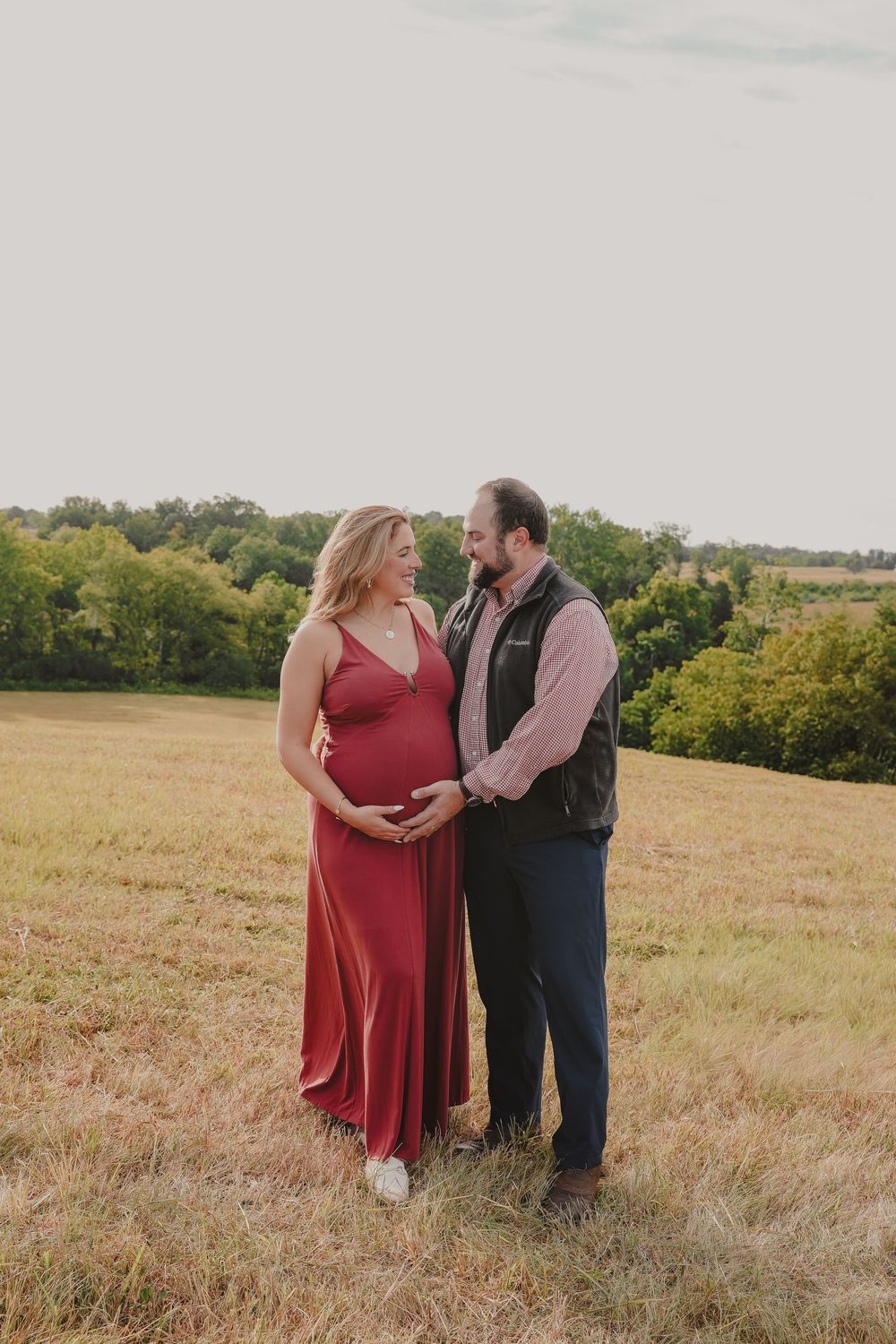 A couple shares an intimate moment in a golden field during sunset as they pose for romantic outdoor portraits.