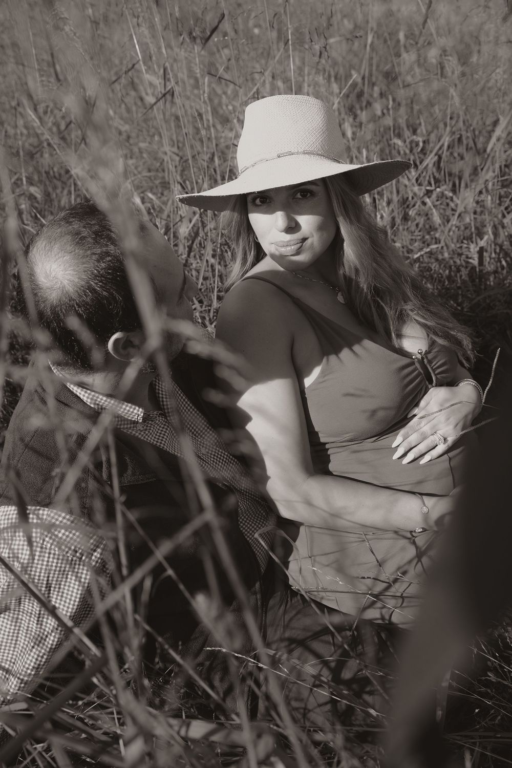 Black and white artistic portraits of someone in a hat among wild grass and natural surroundings.