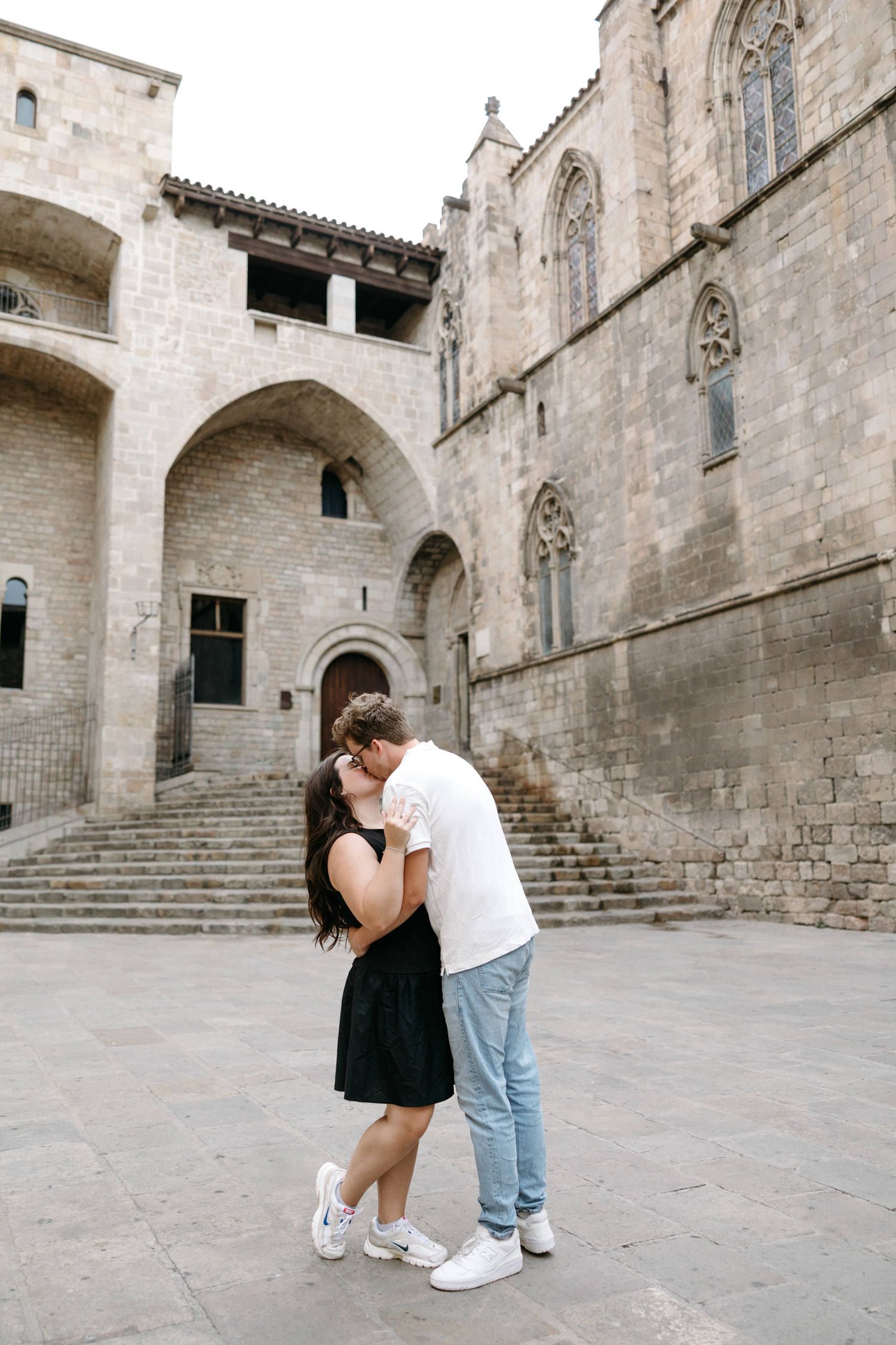 Couple sharing a romantic moment on stone steps of a historic cathedral courtyard.