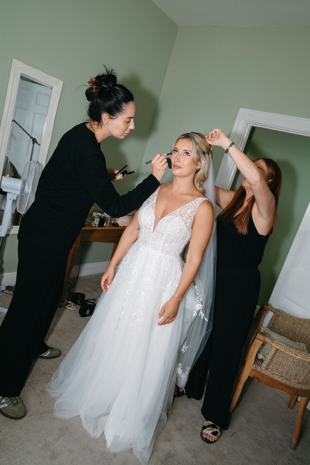 A series of getting ready moments shows someone in a white wedding gown being helped with final preparations before the ceremony.