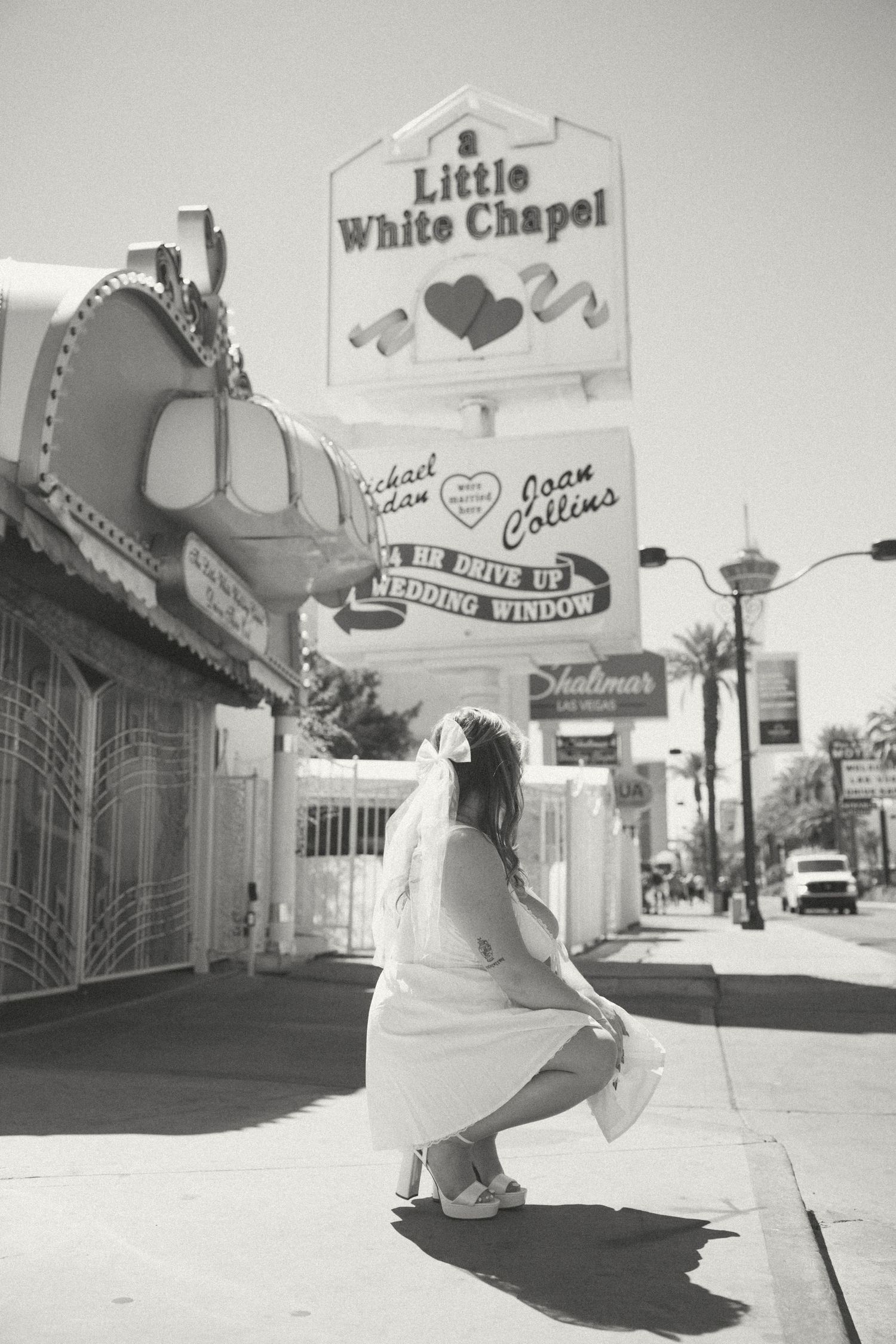 A black and white photo of a bride posing outside the Little White Chapel wedding venue in Las Vegas.