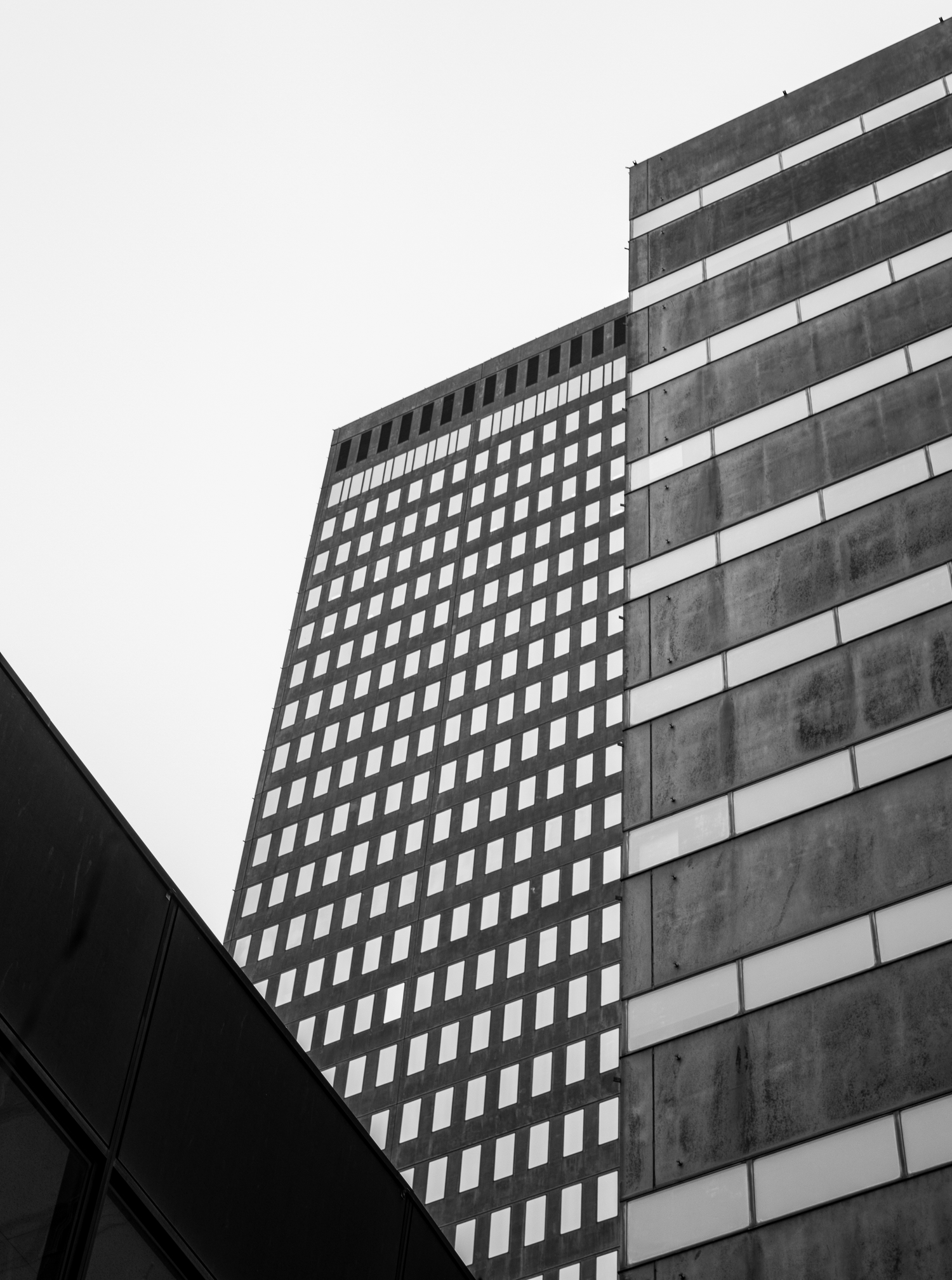 Low angle view of modern office building with geometric pattern of windows in black and white.