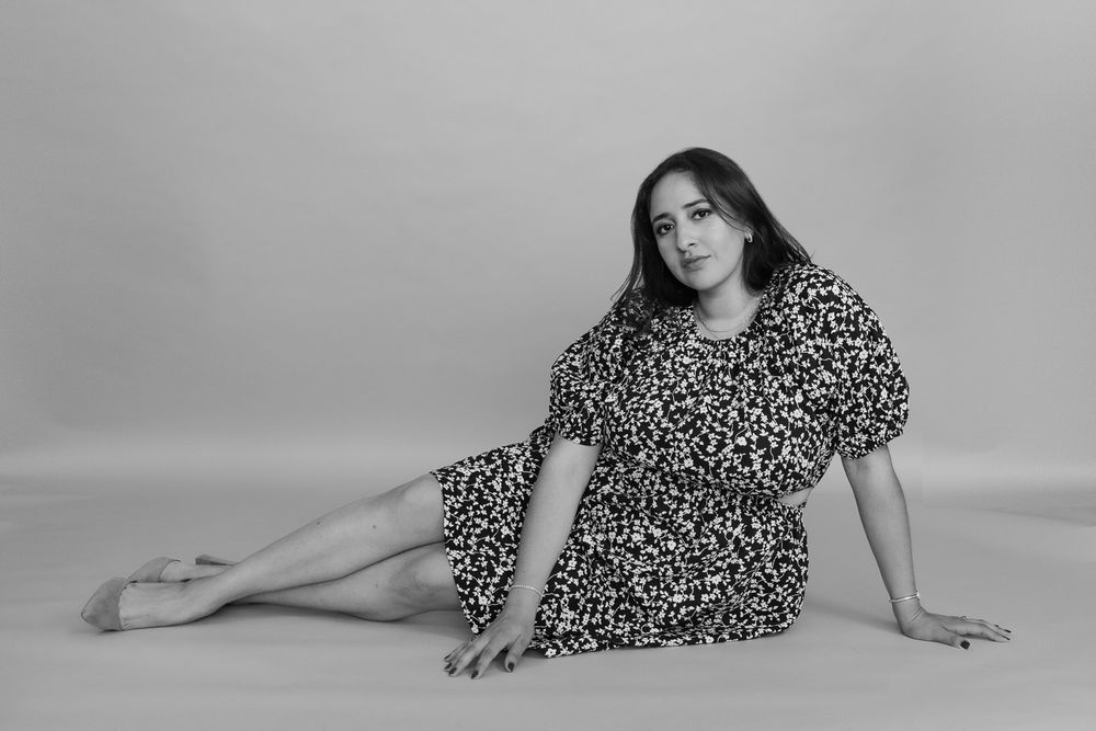 Black and white portrait of model in leopard print dress posing on studio floor.