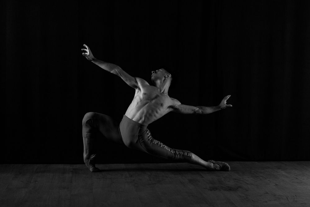 Dramatic black and white capture of a dancer in a dynamic leaping position.