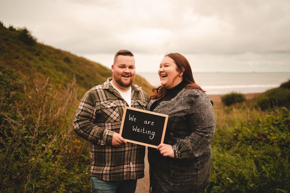 A joyful engagement announcement moment captured on a scenic coastal hillside.