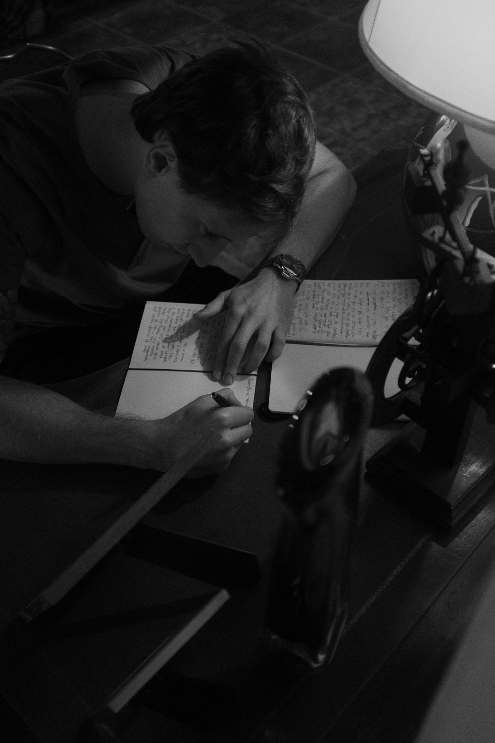 Dark sequence of someone writing or drawing on paper at a desk in low light conditions.