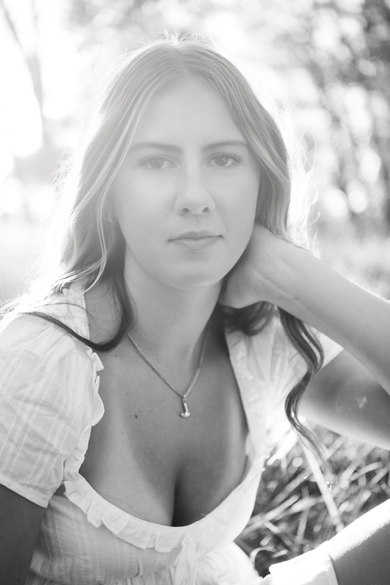 Black and white portrait photo of a woman in a white top with soft lighting and bokeh background effect.