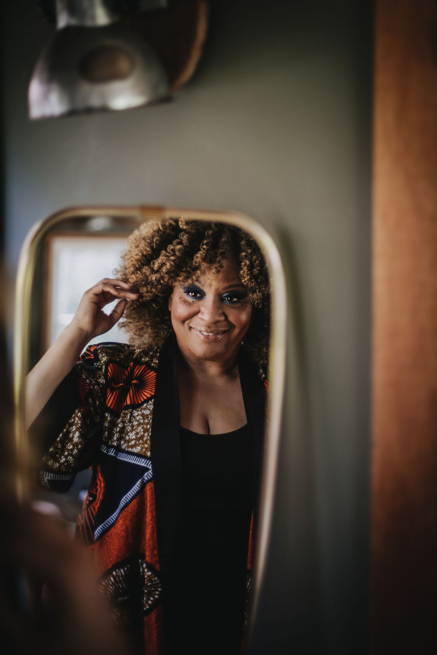 Artistic mirror reflection portraits in moody lighting showing curly hair and casual style.