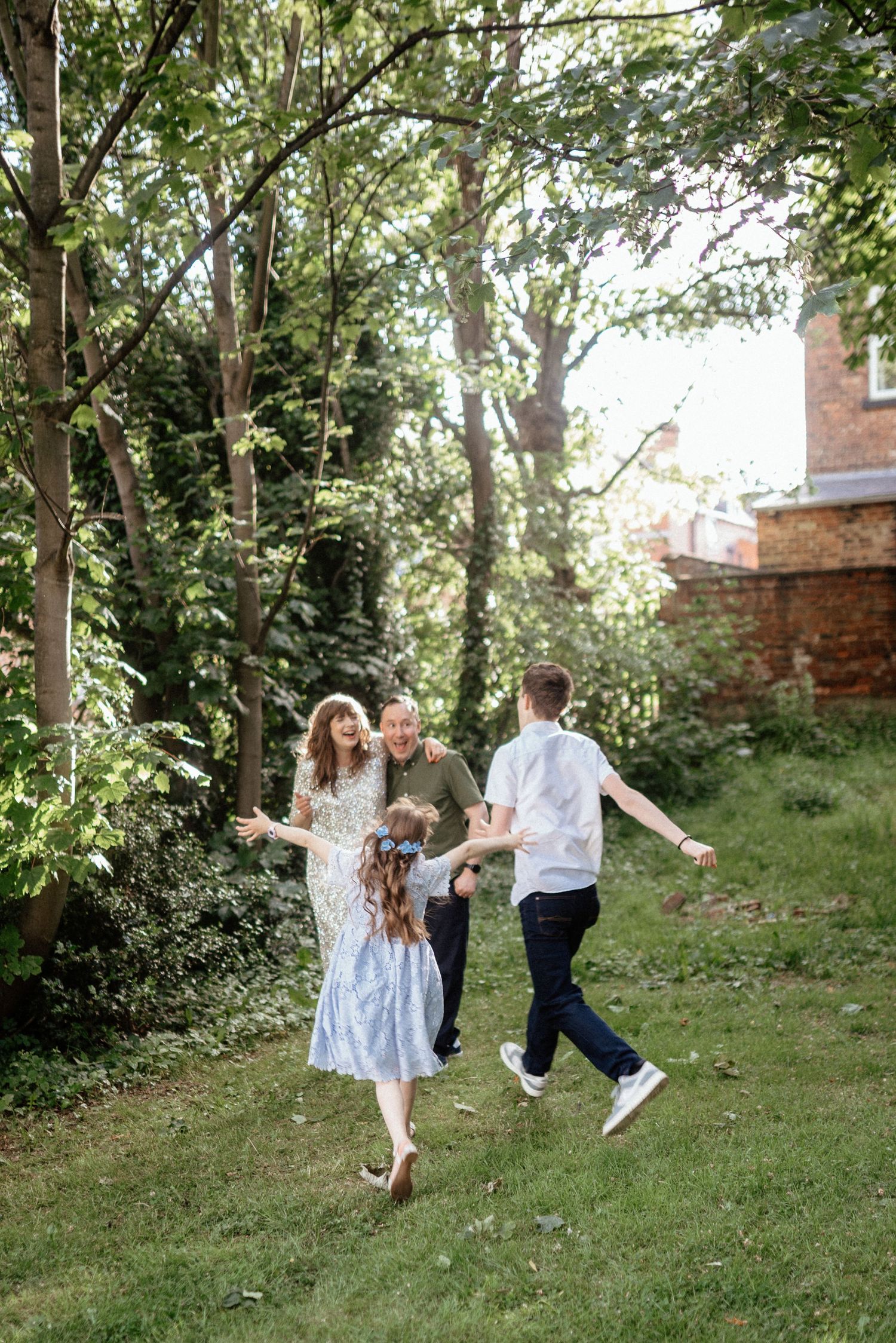 Playful couple running and twirling in a sunlit garden setting.