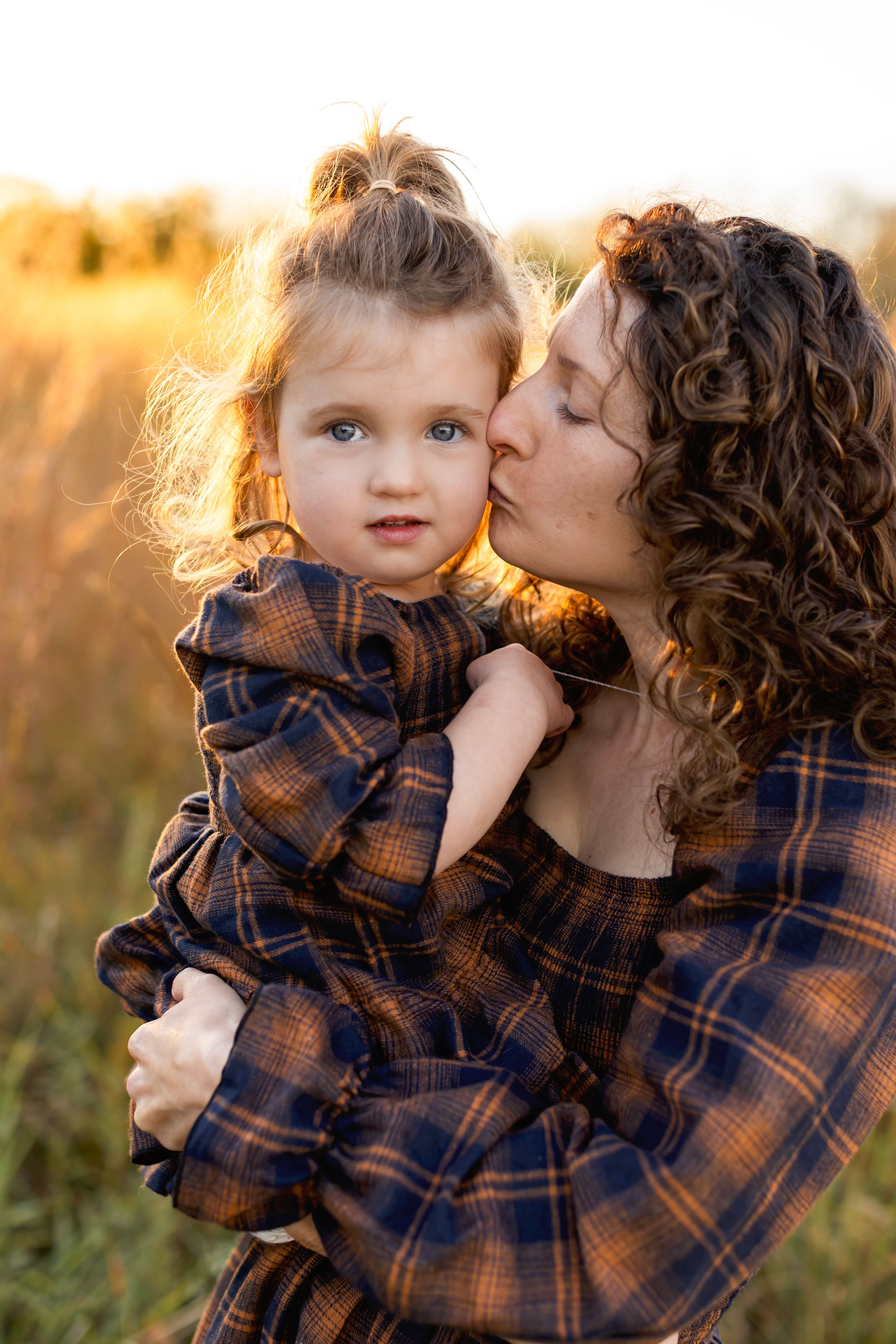 ender moment between parent and child wearing matching plaid shirts during golden hour in a grassy field. Nj Family Photographer in Sussex